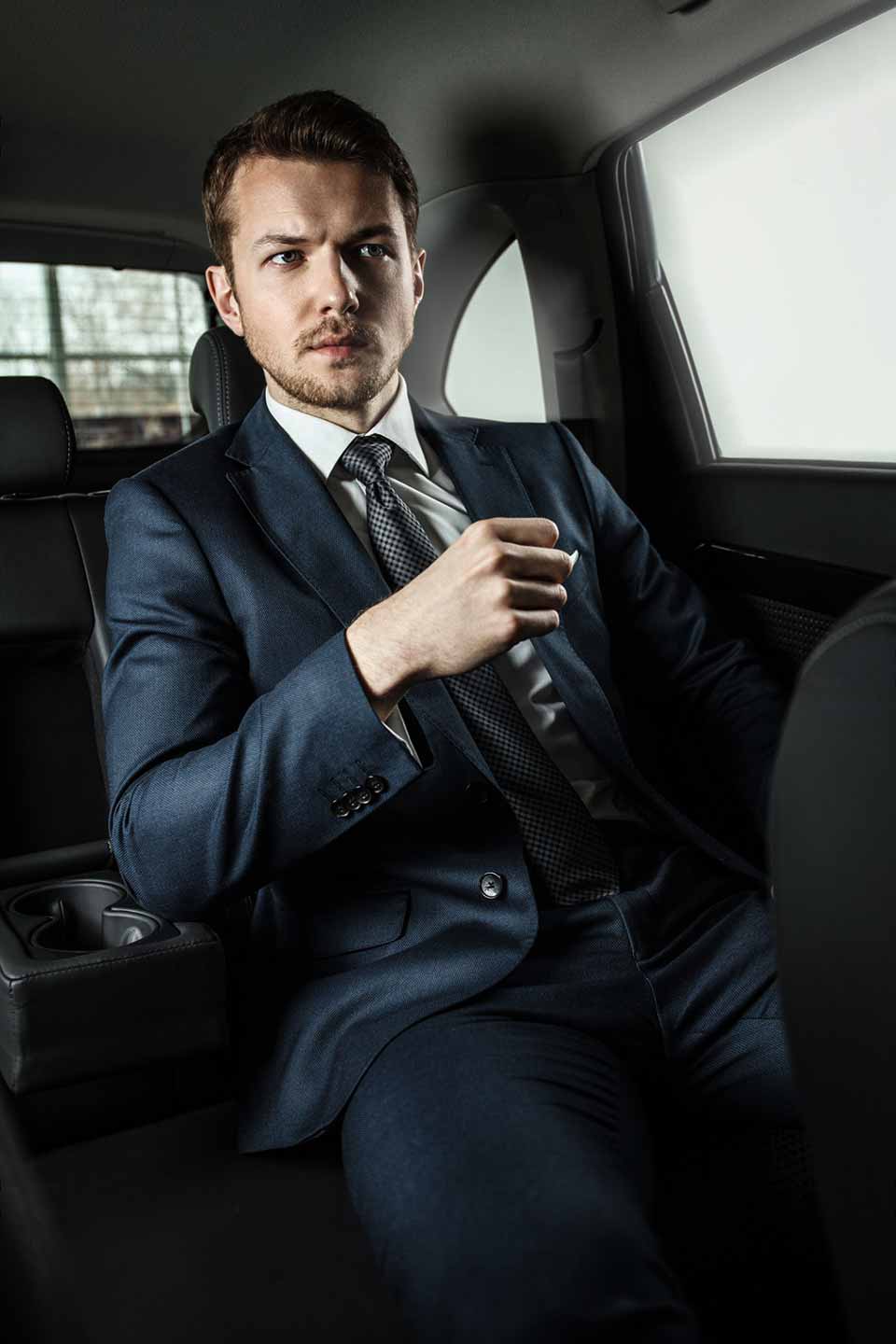 Professional chauffeur ready to greet passenger beside Luxury SUV fleet for executive limo service in Toronto